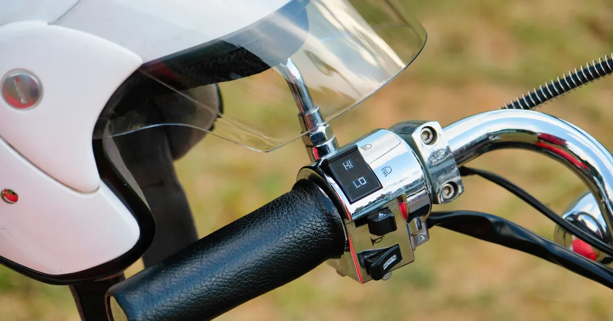 Witte helm met vizier naast het stuur en de schakelaars van een motor